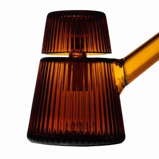 A close-up of the NWTN Home Deco Bubbler, a modern ribbed amber glass piece featuring a conical base, cylindrical top, and slanted handle, displayed against a white background.