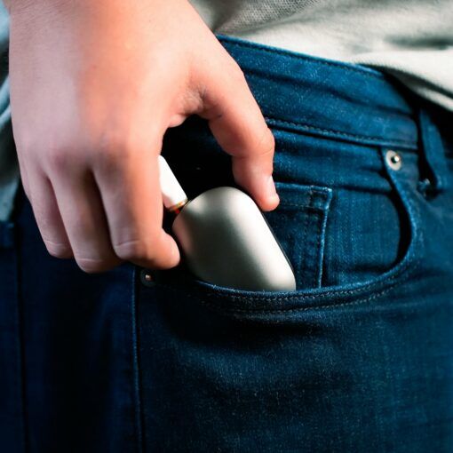 A hand is placing the sleek, silver Freeze Pipe Vape Pen into the front pocket of blue jeans.
