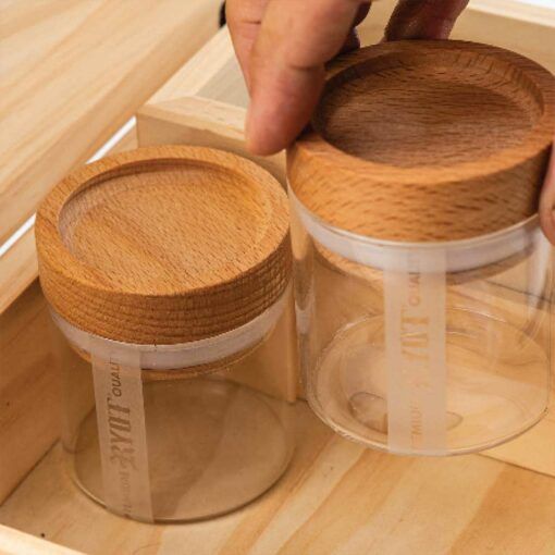A hand lifts a clear glass jar with wooden lid from the HUMIDOR WALNUT COMBO BOX (8X11); another matching jar for cigar storage remains inside the box.