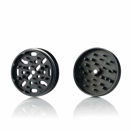 Two black, circular RYOT 4PC SOLID BODY GRINDER parts are displayed side by side on a white background. These metal grinders feature sharp teeth and holes, ensuring dependable grinding performance for every user.