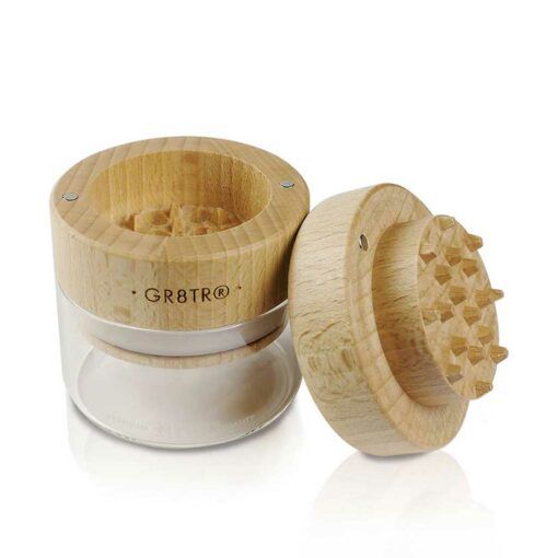 The WOOD GR8TR WITH JAR BODY herb grinder features a transparent base and an engraved lid placed beside it, showcasing its internal grinding teeth and superior craftsmanship.