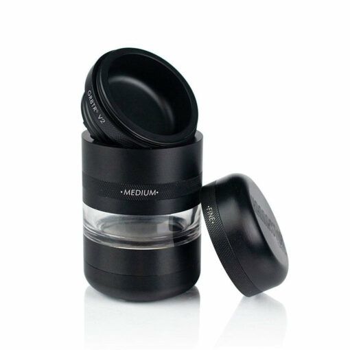 A black RYOT GR8TR JAR BODY GRINDER labeled MEDIUM stands upright with its transparent jar body. The lid and an extra grinding component are removed and set nearby on a white background.