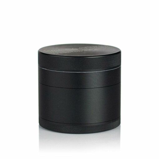 A black, cylindrical RYOT 4PC SOLID BODY GRINDER with textured edges stands upright on a white background, its four stacked parts highlighting the quality craftsmanship of this premium grinder.