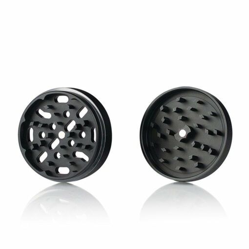 Two black RYOT 4PC JAR BODY GRINDERS are displayed side by side on a white background. The left grinder has multiple holes and sharp teeth, while the right shows a circular tooth pattern with a single center hole.