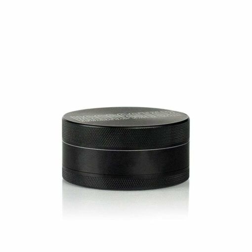 A black, cylindrical RYOT 4PC JAR BODY GRINDER with a textured grip and minimalist design sits on a white background. Horizontal lines divide its two sections for easy handling.