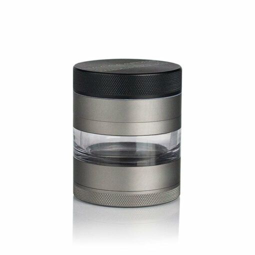 The RYOT 4PC JAR BODY GRINDER is a cylindrical metal grinder with a clear midsection and textured edges for easy grip, showcasing a sleek, modern design against a white background.