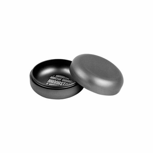 The RYOT GR8TR JAR BODY GRINDER is a round, black matte tin with a removable lid, partially open to show the interior and white text printed on the bottom—blending sleek design with practical features.