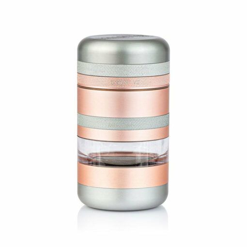 The RYOT GR8TR Jar Body Grinder is a compact, cylindrical grinder with silver and rose gold bands and a transparent middle section that shows the mesh filter inside, displayed against a white background.