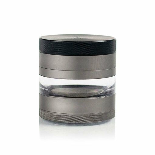 The RYOT 4PC JAR BODY GRINDER, a sleek metallic cylindrical container with textured edges for grip and a transparent middle section, stands upright on a white background. The design is reminiscent of premium 4-piece grinders.