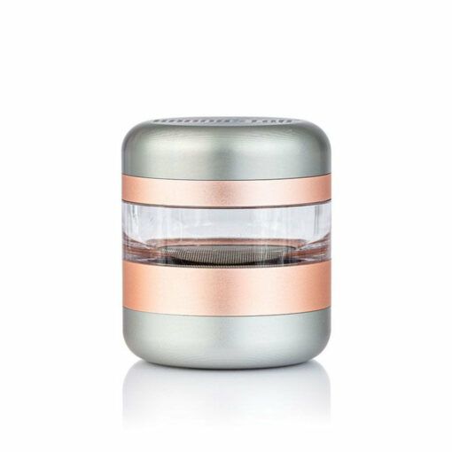 The RYOT GR8TR JAR BODY GRINDER is a compact, cylindrical metallic grinder with a clear middle section and rose gold and silver bands, ideal for grinding herbs or spices; inspired by signature GR8TR design cues.