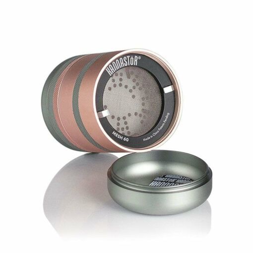 The RYOT GR8TR JAR BODY GRINDER is a cylindrical metal grinder in rose gold and gray, shown partially open to display its mesh screen and grinding teeth, with the lid placed next to it against a white background.