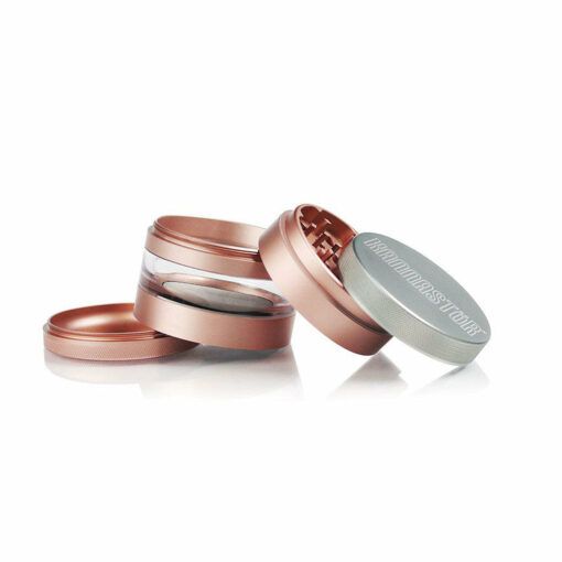A RYOT 4PC JAR BODY GRINDER in rose gold and silver lies open and stacked on a white background, displaying its multiple detachable parts, sharp grinding teeth, and transparent section.