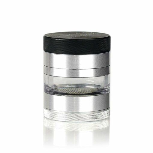 The RYOT 4PC JAR BODY GRINDER, shown in silver and black with a transparent cylindrical body, features multiple compartments and a textured bottom grip for easy use, displayed against a white background.
