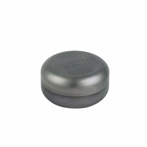 A round, metallic grey RYOT GR8TR SOLID BODY GRINDER with a slightly domed, smooth matte top sits on a white background. Faint text appears on the surface.