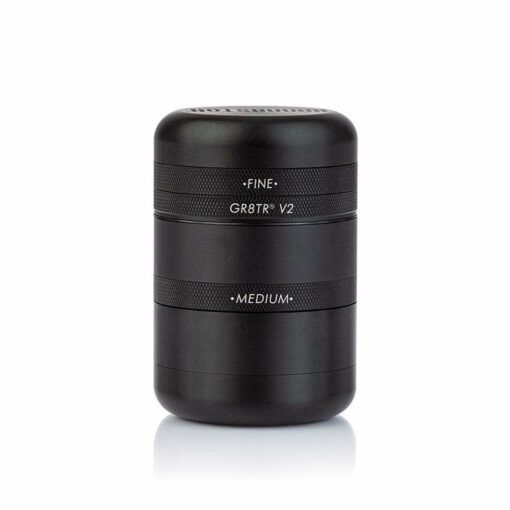 A black RYOT GR8TR SOLID BODY GRINDER with a textured grip, featuring FINE, GR8TR V2, and MEDIUM labels, stands upright on a white background.