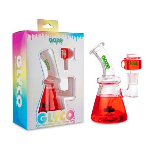A clear Ooze Glyco Bong Glycerin Chilled Glass Water Pipe with red liquid sits by its colorful box labeled GLYCO and Ooze, which highlights the bong as a glycerin-chilled piece for smoother, cooler hits.