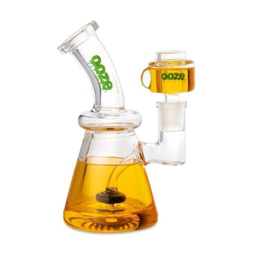 The Ooze Glyco Bong Glycerin Chilled Glass Water Pipe features a clear beaker base filled with orange liquid, a side attachment, and "ooze" printed in green on both pieces for standout style.