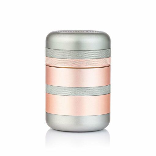 The RYOT GR8TR SOLID BODY GRINDER is a compact, cylindrical grinder with metallic silver and rose gold bands, shown against a plain white background.