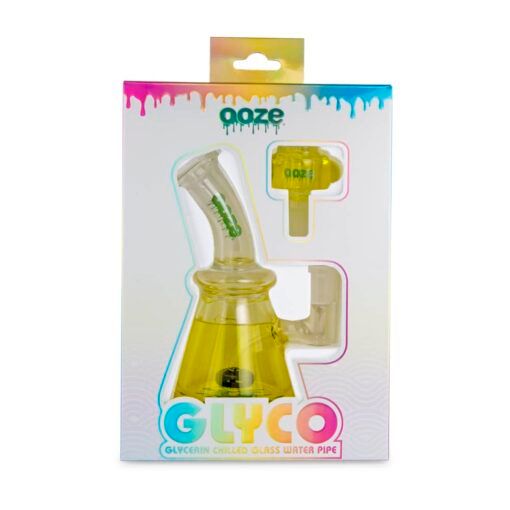 The Ooze Glyco Bong Glycerin Chilled Glass Water Pipe comes boxed with yellow glycerin liquid, visible through a packaging window. The vibrant box has blue, pink, and yellow accents and includes an extra piece.