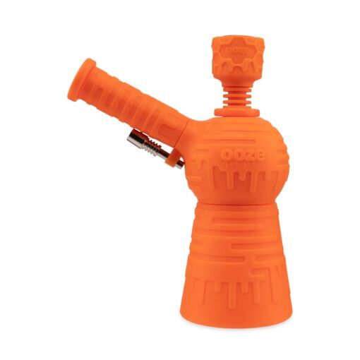 The Ooze Blaster Silicone Glass 4-in-1 Hybrid Water Pipe and Dab Straw is a bright orange piece with a round chamber, angled mouthpiece, cylindrical base, ooze branding, and textured drip-like patterns.