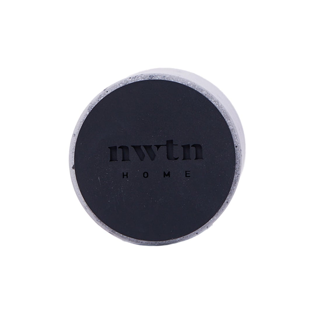 The NWTN Home Anchor Lighter Holder features a round design with a black top, "NWTN" and "HOME" engraved at the center, and a stone-like outer edge shown on a plain white background.