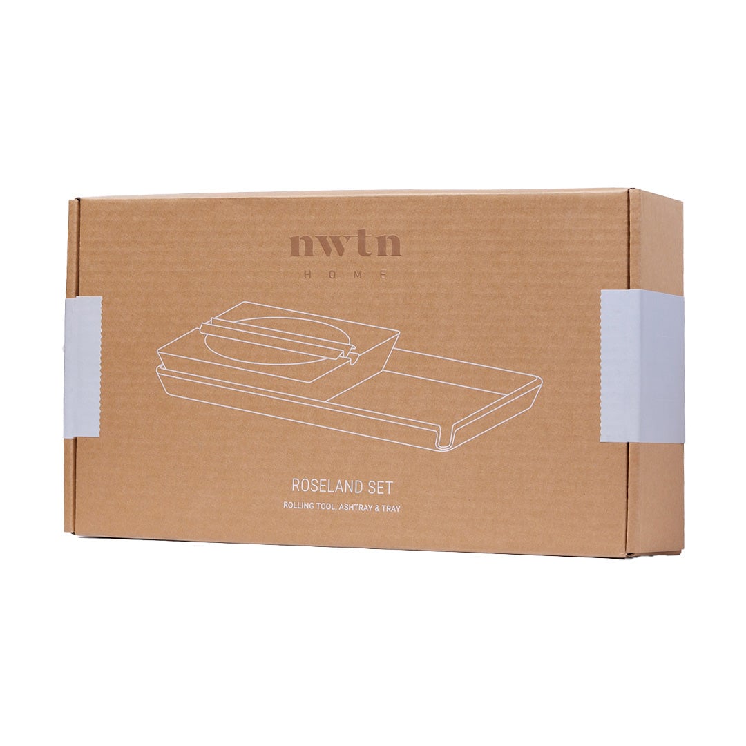 A brown cardboard box labeled NWTN Home contains a NWTN Home Roseland Set Ashtray, with outlined drawings of a rolling tool, ashtray, and tray on the front. White sealing tape secures both sides of the box.