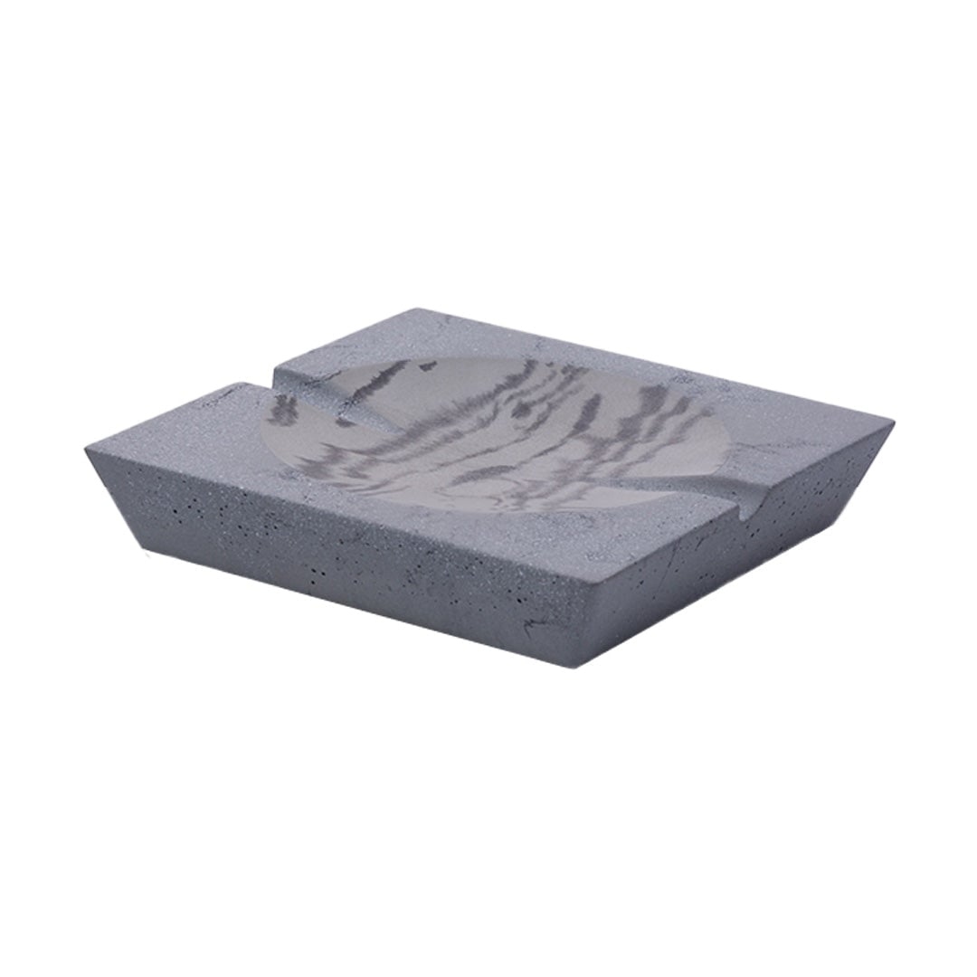 The NWTN Home Roseland Set Ashtray is rectangular, dark gray concrete with a smooth, shallow circular depression, a cigarette notch, and a slightly speckled surface.