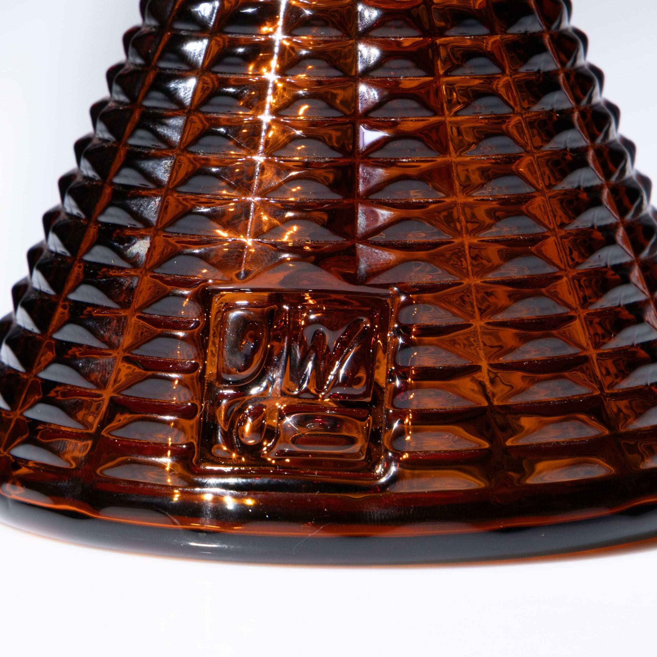 Close-up of the Jane West x Prism Bong - Amber, showcasing its diamond-textured base and a raised OM10 square logo, echoing Jane West’s signature timeless design.