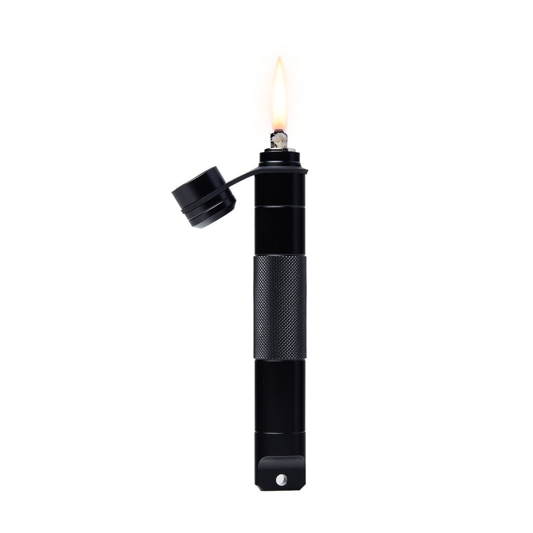 A black, cylindrical metal lighter stands upright, featuring a textured grip and an attached cap flipped open. A tall yellow flame burns at the top, its sleek design resembling the Mj Arsenal Phoenix Baton.