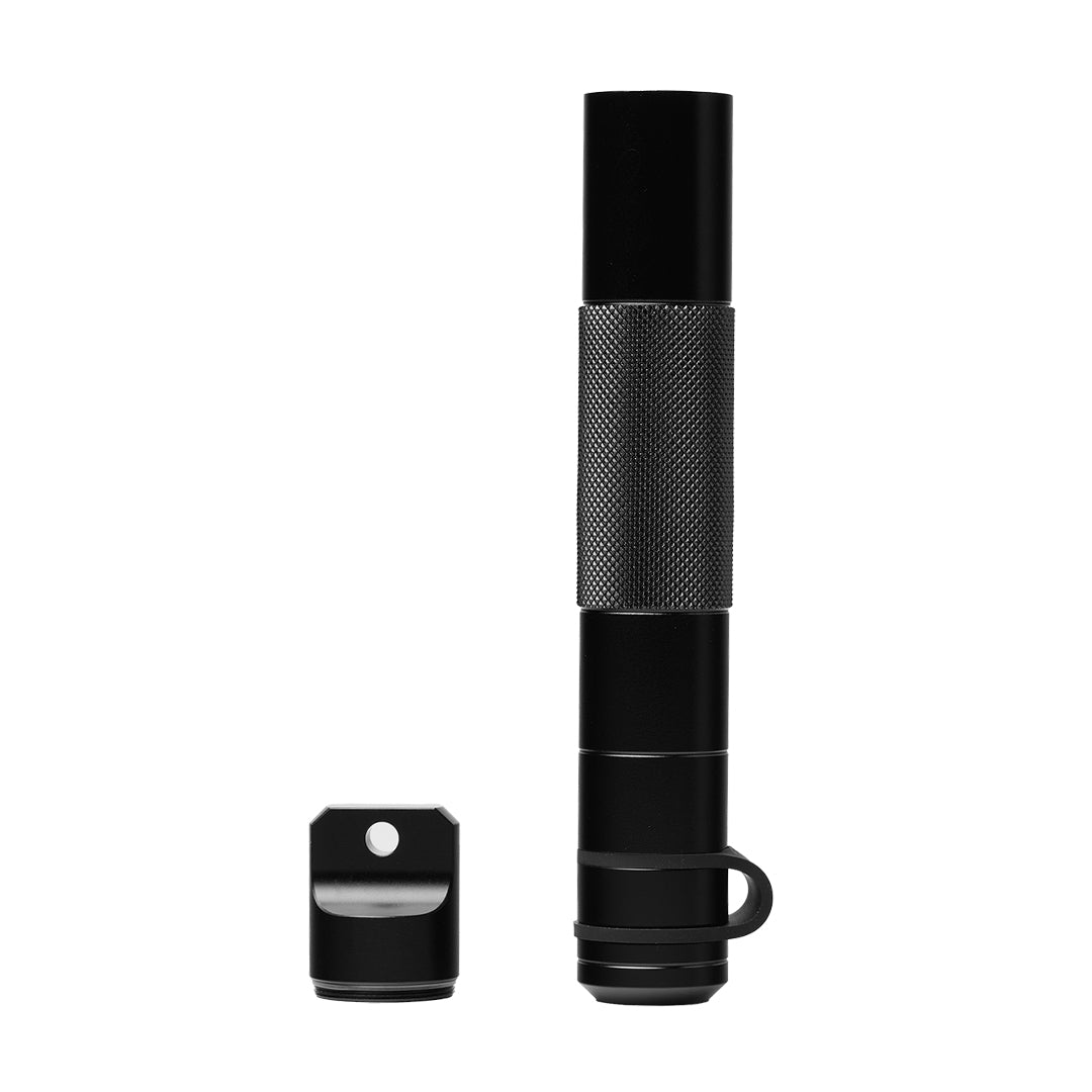 A compact black metal cylinder with a textured grip and a removable cap featuring a lanyard/keychain hole is styled like the Mj Arsenal Phoenix Baton.