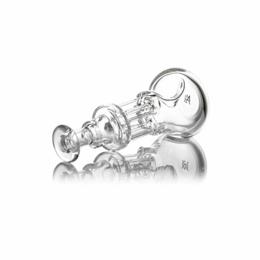 The MJ Arsenal Tetra, a clear glass piece with cylindrical and rounded shapes, lies on its side on a reflective white surface, displaying several connecting sections and an open end.