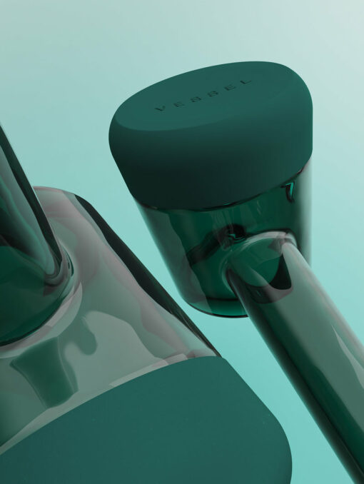 Close-up of two sleek, minimalistic Forge [Emerald] glass containers with matching lids on a pale teal background. One lid is embossed with "VESSEL." Crafted with contemporary precision.