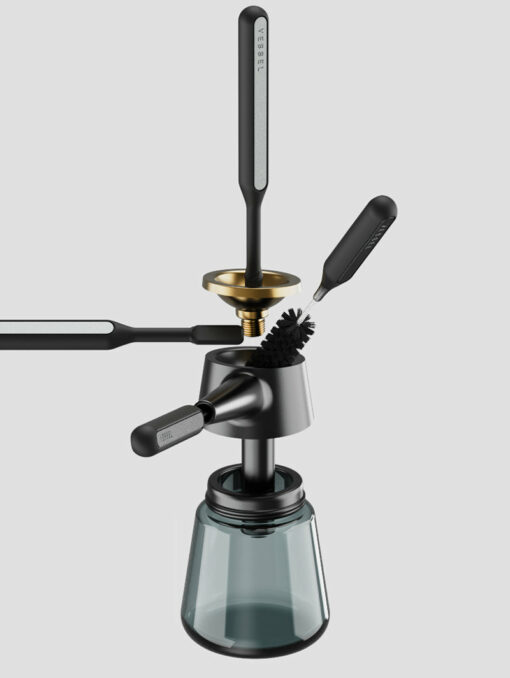 The Care Kit is displayed in an exploded view with its parts separated, including a glass base, metal filter, funnel, brush, and several black-handled utensils arranged on a gray background.