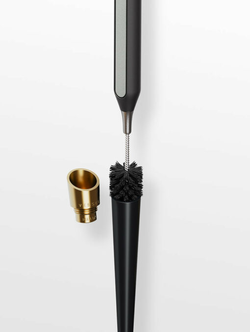 A close-up of the Care Kit, a modern cleaning tool with a slim handle, bristle brush head, and a removable gold-colored cap labeled VESSEL, shown on a white background.
