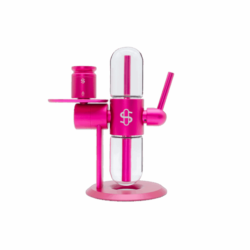 A modern Stündenglass Kompact Gravity Infuser - Pink features transparent glass chambers, a cylindrical body, and a side-mounted cup on a round base, shown against a plain white background.