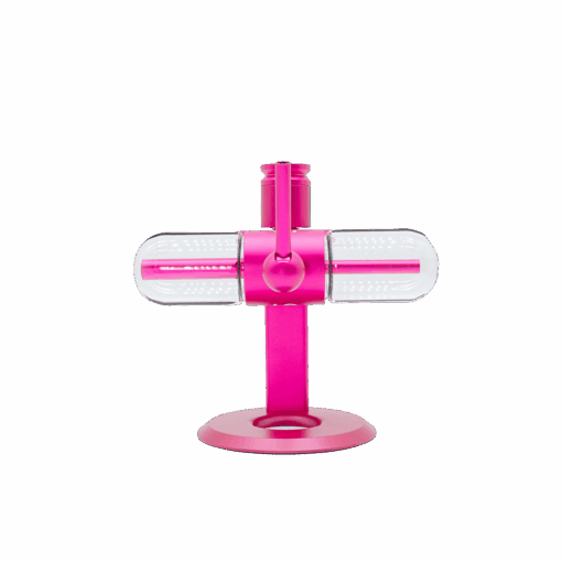 The Stündenglass Kompact Gravity Infuser - Pink inspires this modern pink pet toy featuring a vertical stand, a horizontal transparent capsule with small white dots, and treat-dispensing action. Presented on a plain white background.