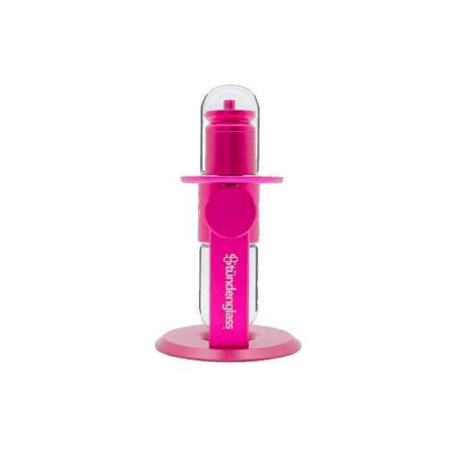 The Stündenglass Kompact Gravity Infuser - Pink is a cylindrical device with a bright pink finish, clear top dome, two side openings, and a round base, positioned upright against a plain white background.