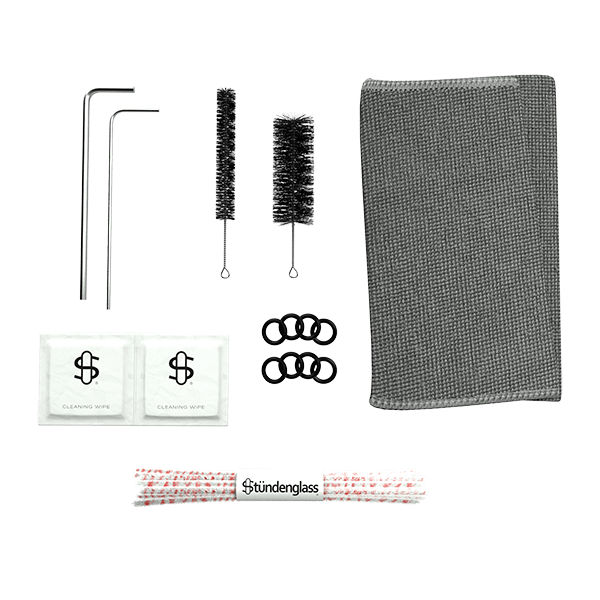 Cleaning kit for your Stündenglass Kompact Gravity Infuser - Pink shown on a white background with two metal rods, two cleaning brushes, a gray textured cloth, two wipes, black rubber rings, and a Stündenglass pipe cleaner.