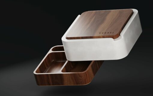 Ash is a modern storage box with a white outer shell and wooden interior, featuring two compartments. Its matching wooden lid, labeled "VESSEL," is partially lifted above the box, all set against a dark background.