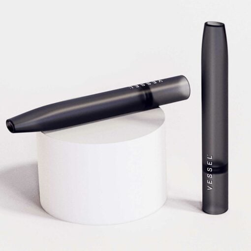 A sleek, gray Air vape pen is displayed by VESSEL, with one standing upright and another lying horizontally on a white cylindrical pedestal against a light background.