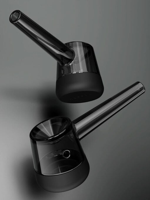 Two Forge [Black] glass pipes, featuring cylindrical black bases and clear angled stems, are set against a smooth grey background, creating a minimalistic and contemporary vibe.