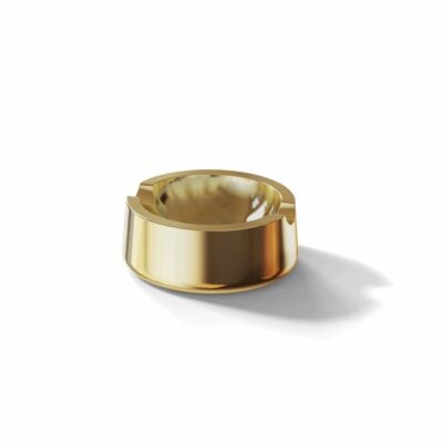 The Ember [Gold] ashtray features a shiny, reflective gold surface with three grooves and rests on a white background, casting a soft shadow.