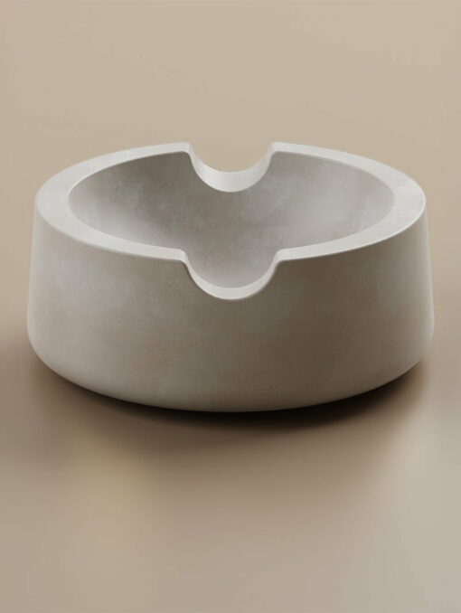 The Ember [Concrete] is a modern round ember-gray concrete bowl with a smooth matte finish and two curved rim notches, shown on a neutral beige surface.