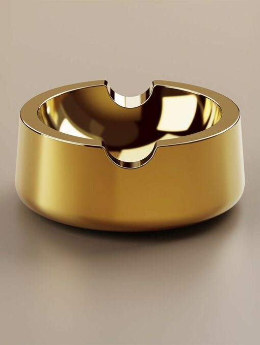 The Ember [Gold] ashtray features a shiny ember-gold finish, smooth rounded design, and three notches for holding cigarettes, elegantly displayed on a neutral surface.