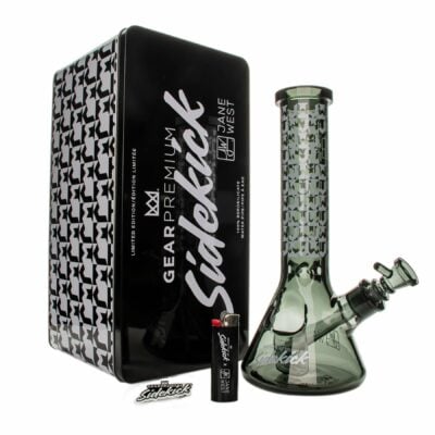 A Limited Edition JW Sidekick by GEAR Premium® glass bong sits beside a black lighter and a black houndstooth tin box featuring GEAR Premium® Sidekick branding.