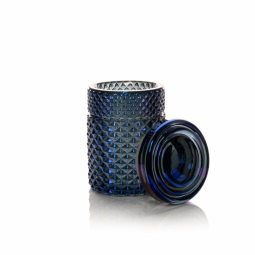 A Twenties Collection Jar | Midnight, featuring dark blue textured glass with a geometric diamond pattern, sits on a white background. Its lid is off and leaning against the jar, exposing the open midnight-hued top.