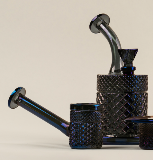 The Twenties Collection Water Pipe | Midnight features dark, textured glass with geometric patterns, a curved spout and lid, and an angled handle—capturing midnight elegance against a light beige background.