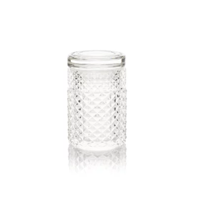 The Twenties Collection Jar | Clear stands upright on a white surface, its diamond-patterned texture reflecting light. Complete with a matching glass lid, this elegant, empty jar is ideal for stylish collection display.