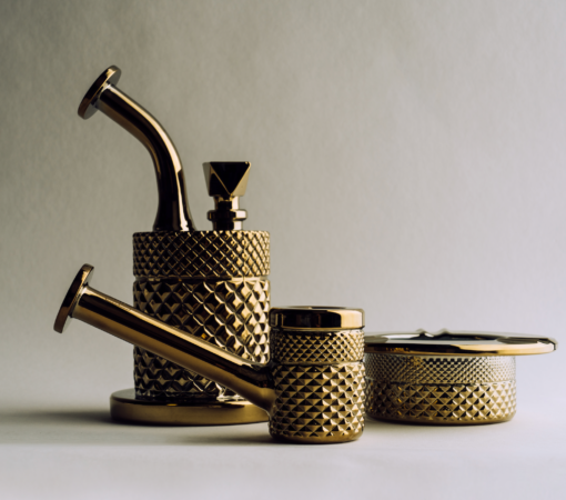 The Twenties Collection Ashtray in Gold, showcased on a neutral background with soft lighting, highlights its shiny, textured surface and art deco-inspired pattern.