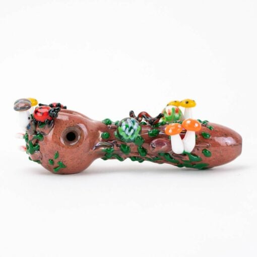The Empire Glassworks Bug's Life Small Spoon Pipe features brown glass with colorful mushrooms, leaves, and vines, creating a whimsical forest vibe reminiscent of a Bug's Life against a plain white backdrop.